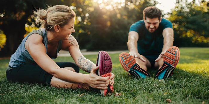 two individuals performing stretching exercises on a grassy field