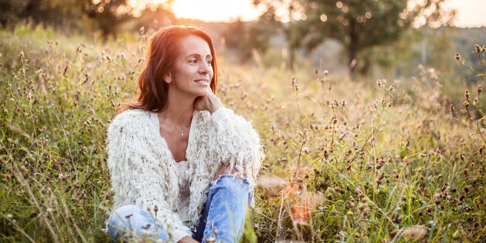 a person sitting in a field surrounded by greenery and small flowers