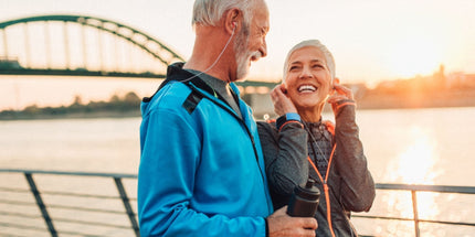 a mature couple walking along the waterside smiling at eachother