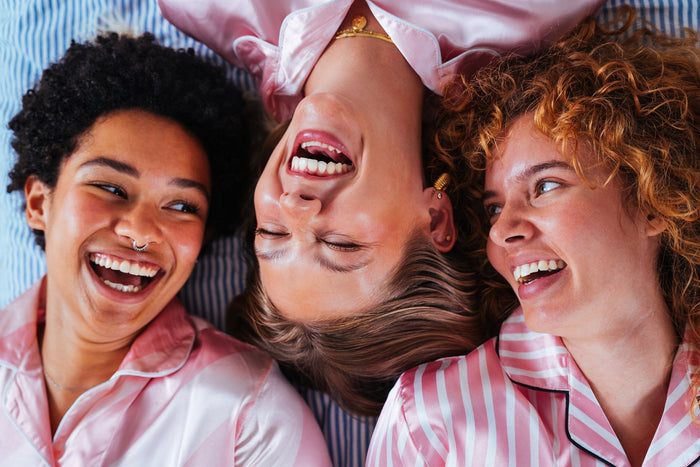 3 women wearing pink pyjamas laughing with eachother