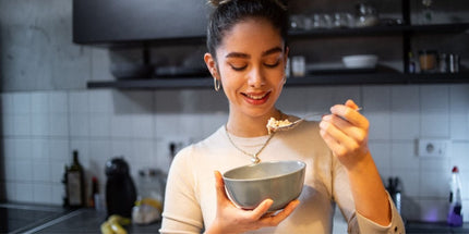 A person holding a bowl and spoon in a kitchen.