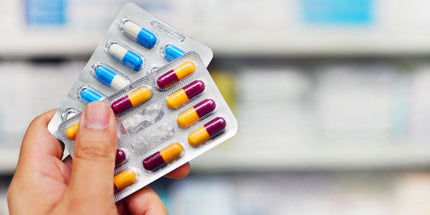 a hand holding a blister pack of colourful capsules