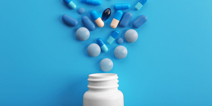 a white bottle with blue capsules spilling out