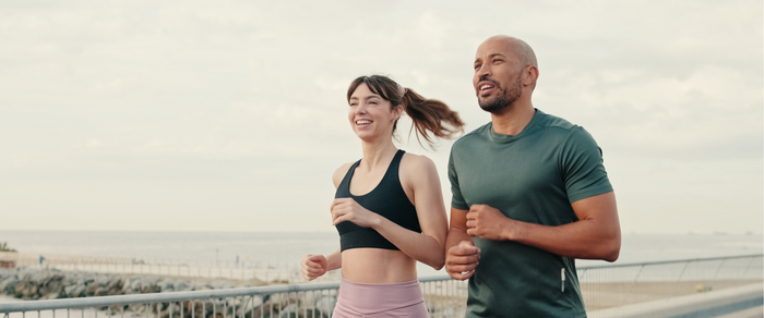Healthy couple running on footpath along beach